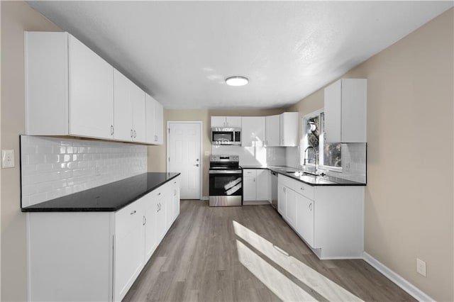 kitchen with sink, stainless steel appliances, backsplash, light hardwood / wood-style floors, and white cabinets