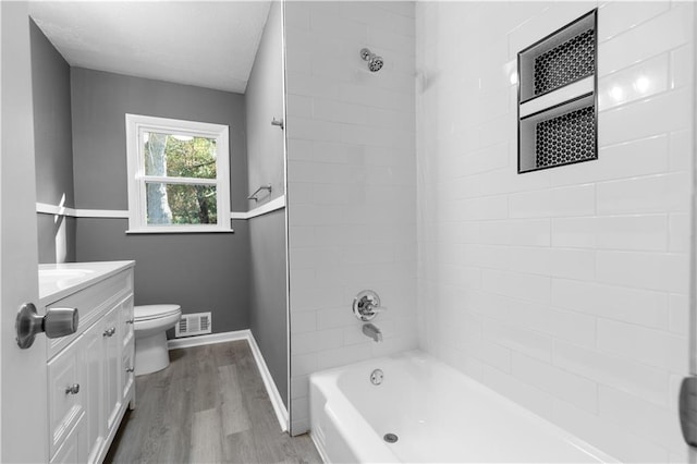 full bathroom featuring vanity, wood-type flooring, tiled shower / bath combo, and toilet