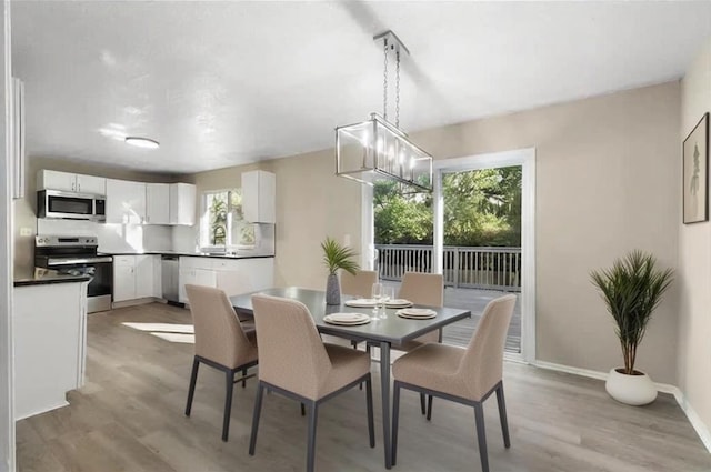 dining space with sink, an inviting chandelier, and light wood-type flooring