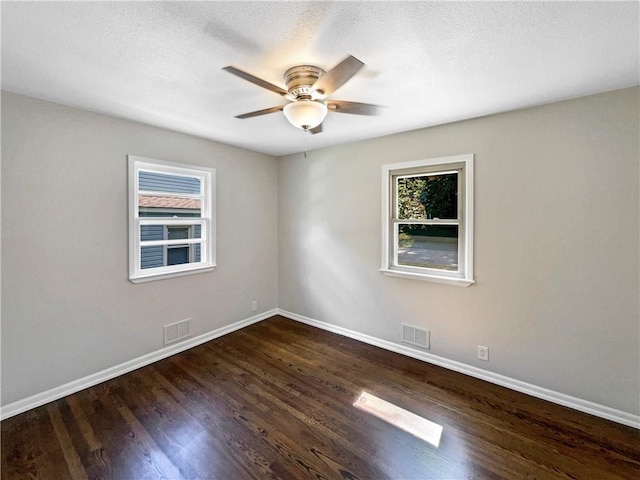 empty room featuring a textured ceiling, dark wood-type flooring, and ceiling fan