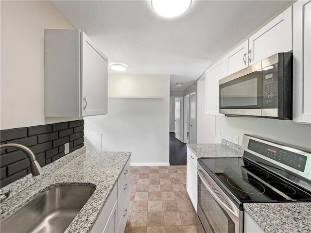 kitchen featuring sink, white cabinetry, stainless steel appliances, light stone countertops, and decorative backsplash