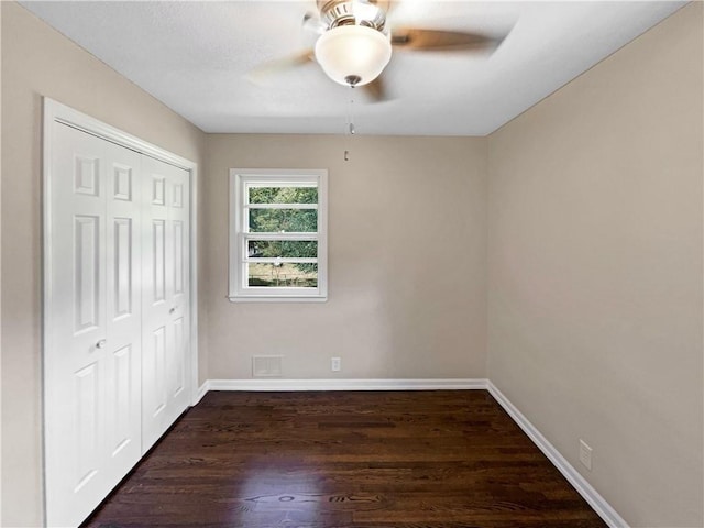 unfurnished bedroom with ceiling fan, a closet, and dark hardwood / wood-style floors