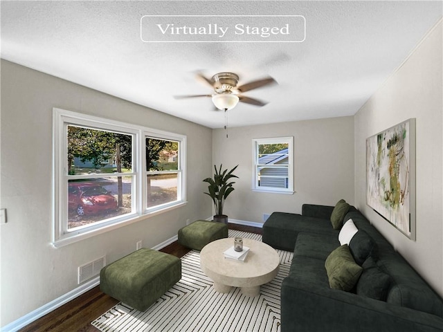 living room featuring a textured ceiling, wood-type flooring, and ceiling fan