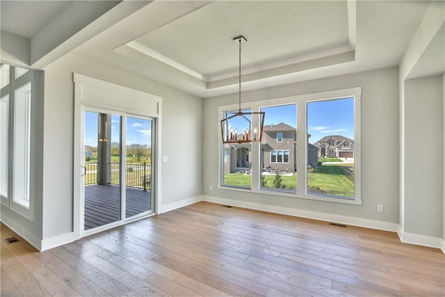 unfurnished dining area featuring a healthy amount of sunlight, light hardwood / wood-style flooring, and a notable chandelier