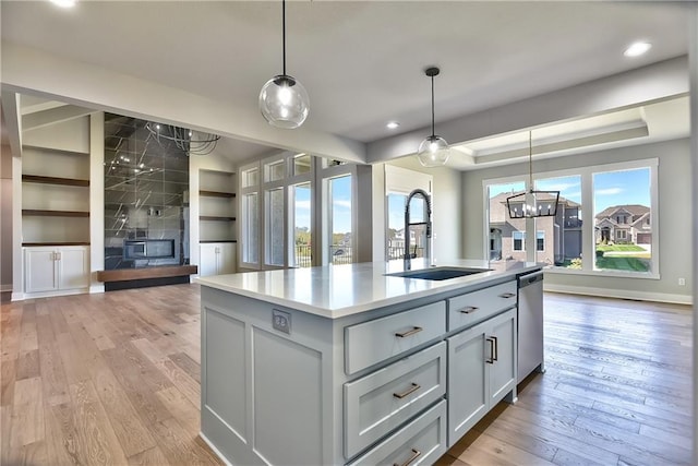 kitchen featuring a center island with sink, a fireplace, pendant lighting, and a wealth of natural light