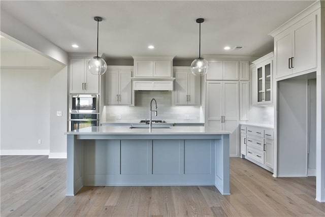 kitchen featuring pendant lighting, light wood-type flooring, and white cabinets