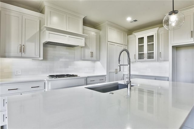 kitchen featuring white cabinets, hanging light fixtures, sink, backsplash, and stainless steel gas stovetop