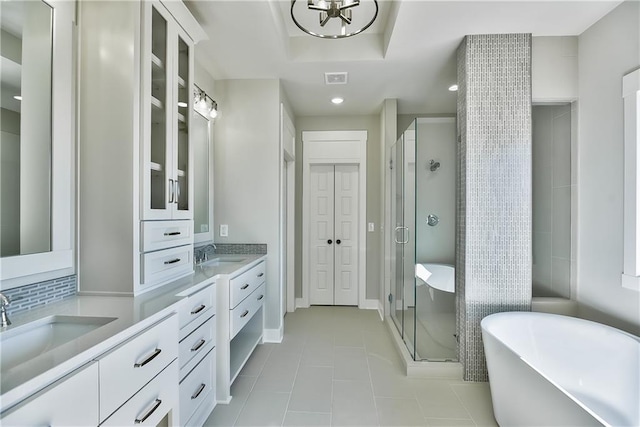 bathroom featuring independent shower and bath, vanity, a tray ceiling, and tile patterned floors