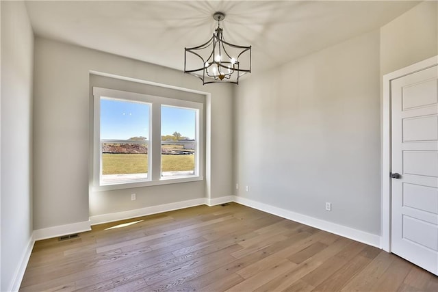 unfurnished room featuring wood-type flooring and a notable chandelier