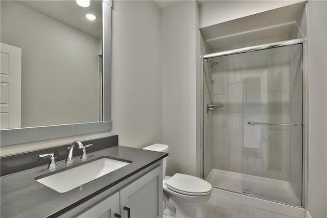 bathroom featuring tile patterned flooring, a shower with door, vanity, and toilet