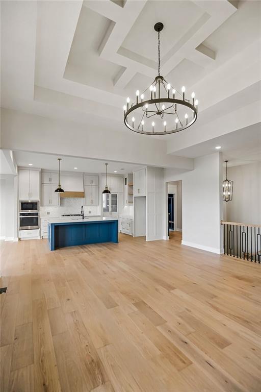 17504 Acton St, Overland Park, KS 66085 - unfurnished living room with an inviting chandelier, coffered ceiling, light wood-style flooring, baseboards, and recessed lighting