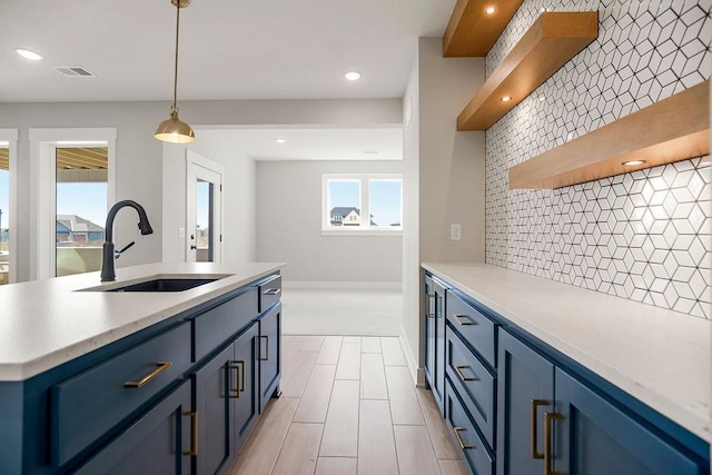 17504 Acton St, Overland Park, KS 66085 - kitchen featuring open shelves, backsplash, a sink, hanging light fixtures, and blue cabinetry