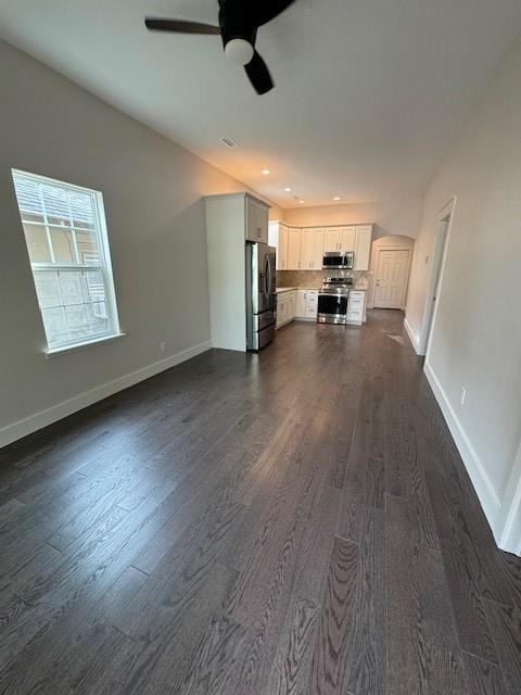 unfurnished living room with ceiling fan and dark wood-type flooring