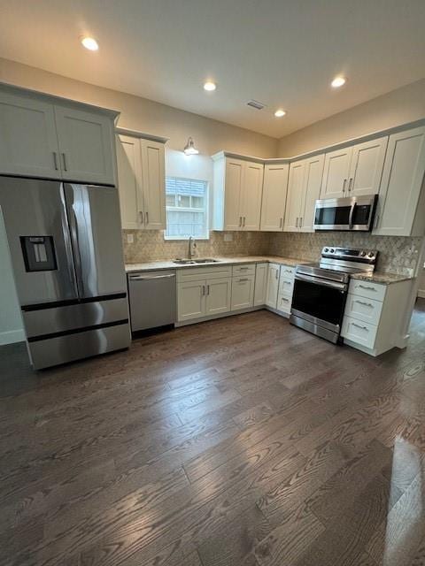 kitchen with backsplash, appliances with stainless steel finishes, dark hardwood / wood-style floors, and sink