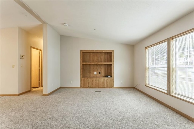 carpeted empty room featuring vaulted ceiling