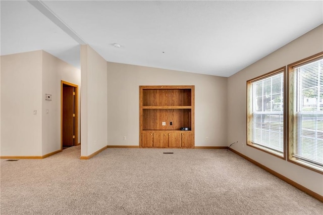 carpeted empty room featuring lofted ceiling and a wealth of natural light