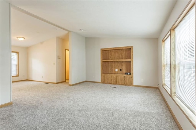 carpeted spare room with lofted ceiling and plenty of natural light