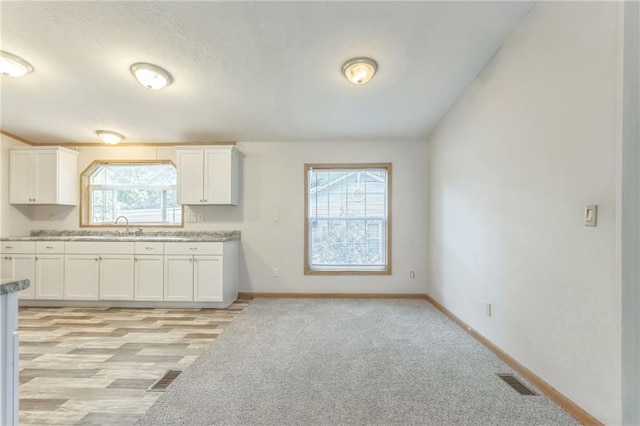 kitchen featuring light hardwood / wood-style floors, white cabinetry, and plenty of natural light