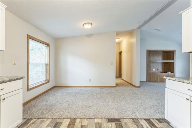 unfurnished dining area featuring light hardwood / wood-style floors and vaulted ceiling