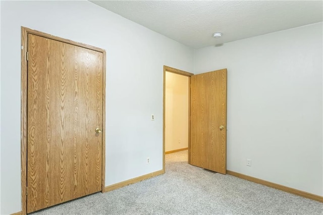 unfurnished bedroom featuring a textured ceiling, light colored carpet, and a closet