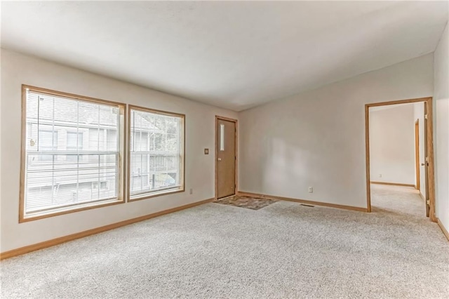 carpeted spare room featuring vaulted ceiling