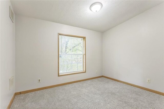 carpeted spare room featuring a textured ceiling