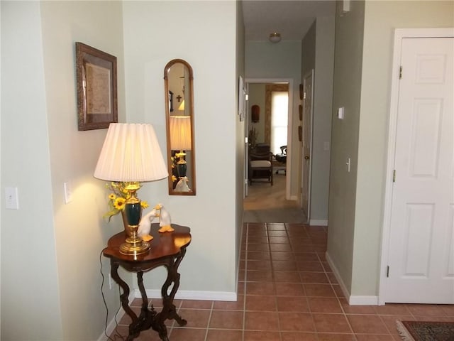 hallway with dark tile patterned flooring and baseboards