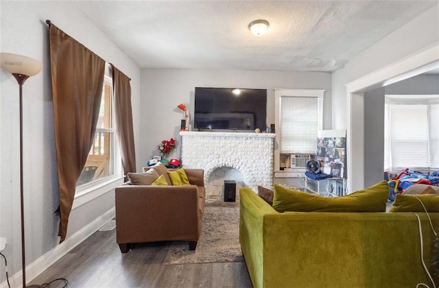 living room with cooling unit, a textured ceiling, a fireplace, and dark wood-type flooring