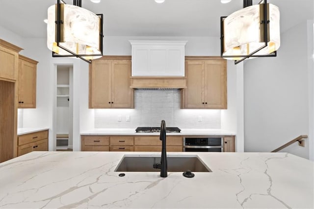 kitchen with sink, gas stovetop, tasteful backsplash, oven, and decorative light fixtures