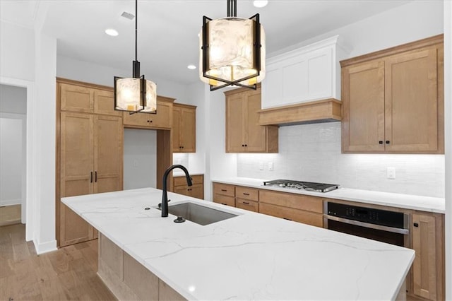 kitchen with sink, a kitchen island with sink, decorative light fixtures, decorative backsplash, and appliances with stainless steel finishes