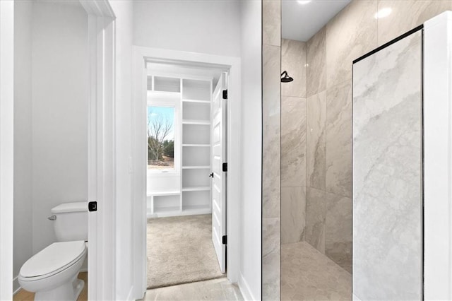 bathroom featuring tiled shower and toilet