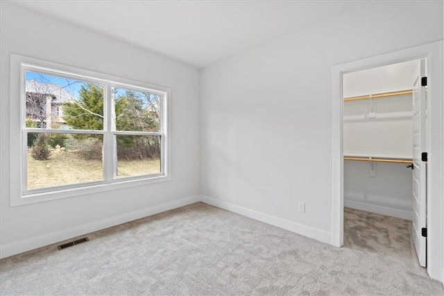 unfurnished bedroom with a spacious closet, a closet, and light carpet