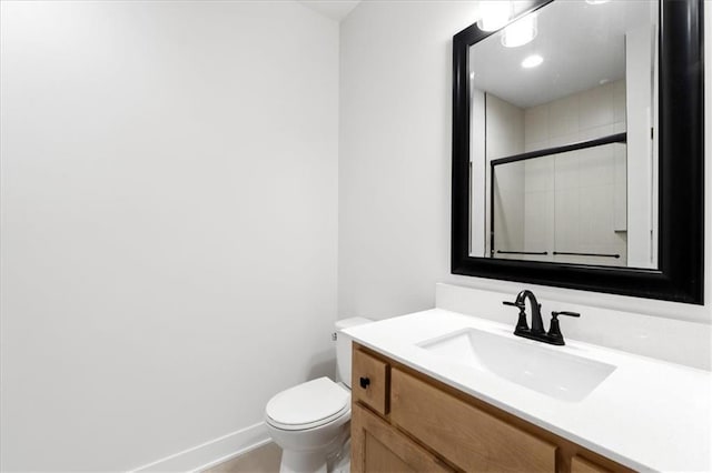 bathroom featuring a shower with door, vanity, and toilet