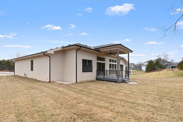 rear view of property featuring a yard, a deck, and ceiling fan