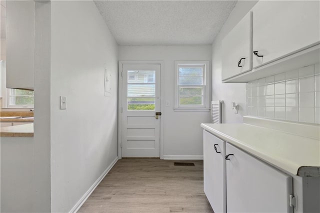 washroom with cabinets, a textured ceiling, and light wood-type flooring