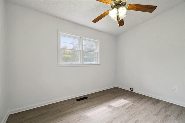 empty room featuring ceiling fan, hardwood / wood-style flooring, and a textured ceiling