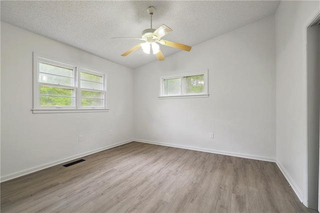 spare room with a healthy amount of sunlight, lofted ceiling, ceiling fan, and light hardwood / wood-style flooring