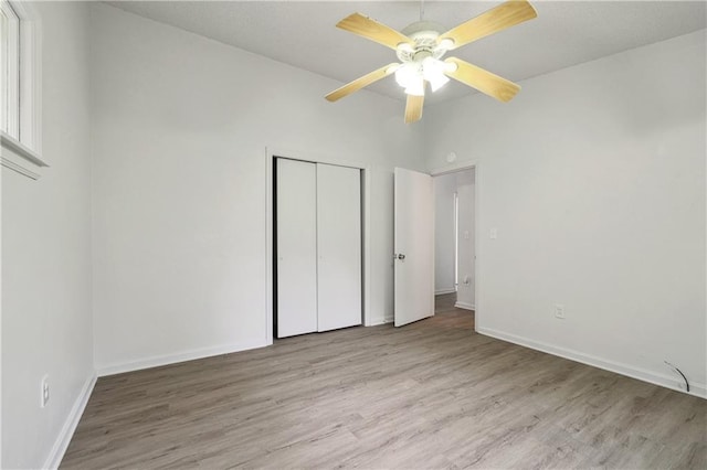 unfurnished bedroom with ceiling fan, light wood-type flooring, and a closet