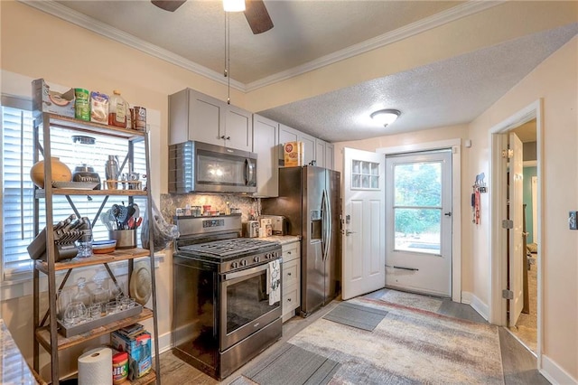 kitchen featuring gray cabinetry, crown molding, stainless steel appliances, and plenty of natural light