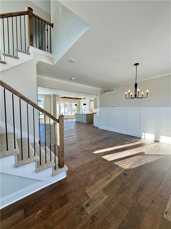 interior space featuring a notable chandelier, dark wood-style floors, stairs, and ornamental molding