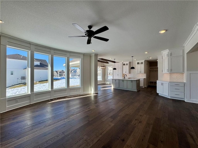 unfurnished living room featuring sink, dark hardwood / wood-style flooring, a textured ceiling, and ceiling fan