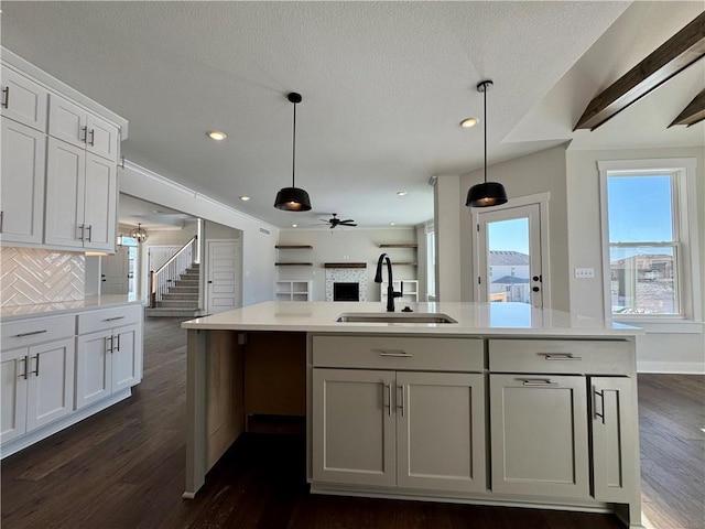 kitchen with hanging light fixtures, tasteful backsplash, white cabinetry, ceiling fan, and sink