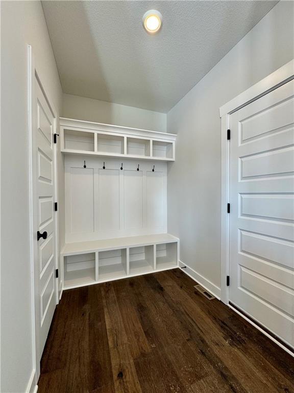 mudroom featuring a textured ceiling and dark wood-type flooring