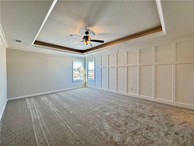 unfurnished bedroom featuring carpet, ceiling fan, a tray ceiling, and crown molding