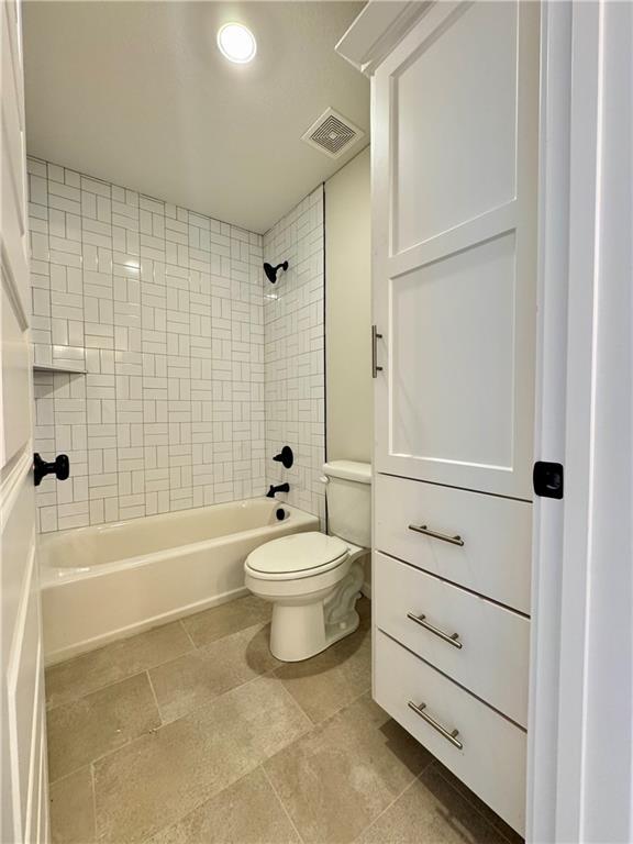 bathroom with toilet and tiled shower / bath