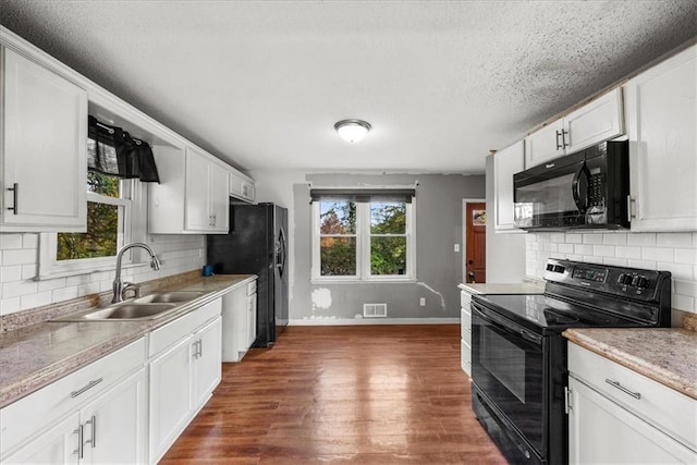 kitchen featuring sink, black appliances, dark hardwood / wood-style flooring, white cabinets, and tasteful backsplash