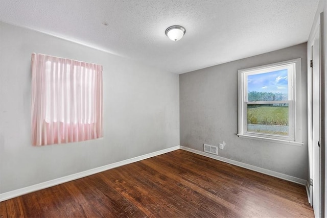 unfurnished room featuring a textured ceiling and dark hardwood / wood-style flooring