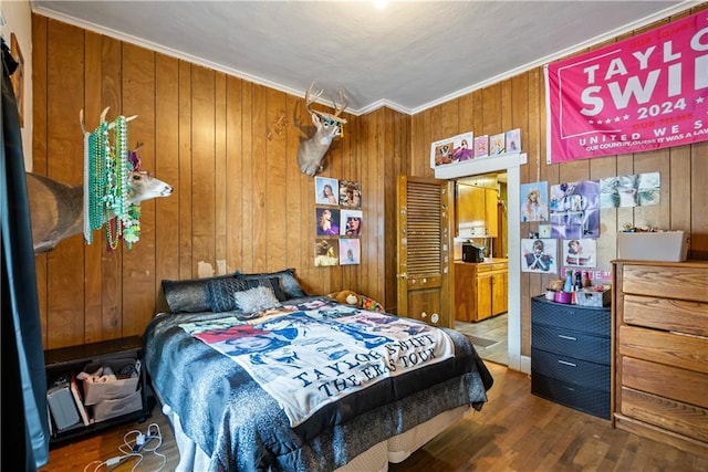 bedroom featuring crown molding, wood walls, and hardwood / wood-style floors