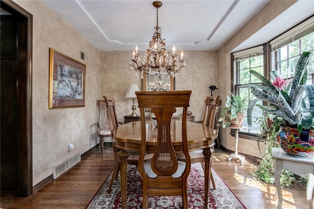 dining space featuring an inviting chandelier, dark wood-type flooring, and a textured ceiling