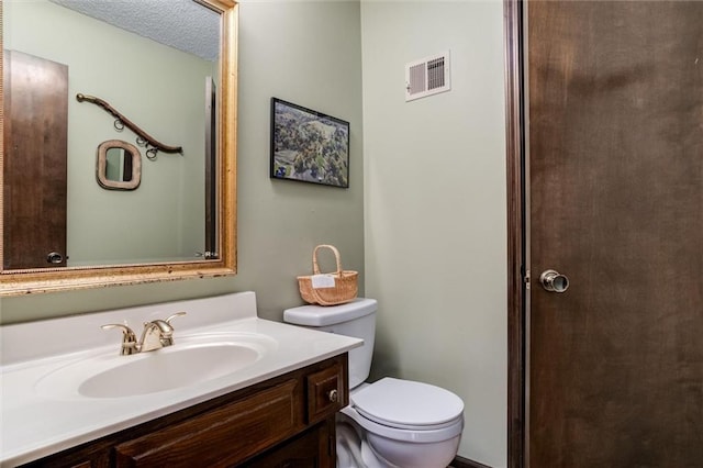 bathroom featuring a textured ceiling, vanity, and toilet